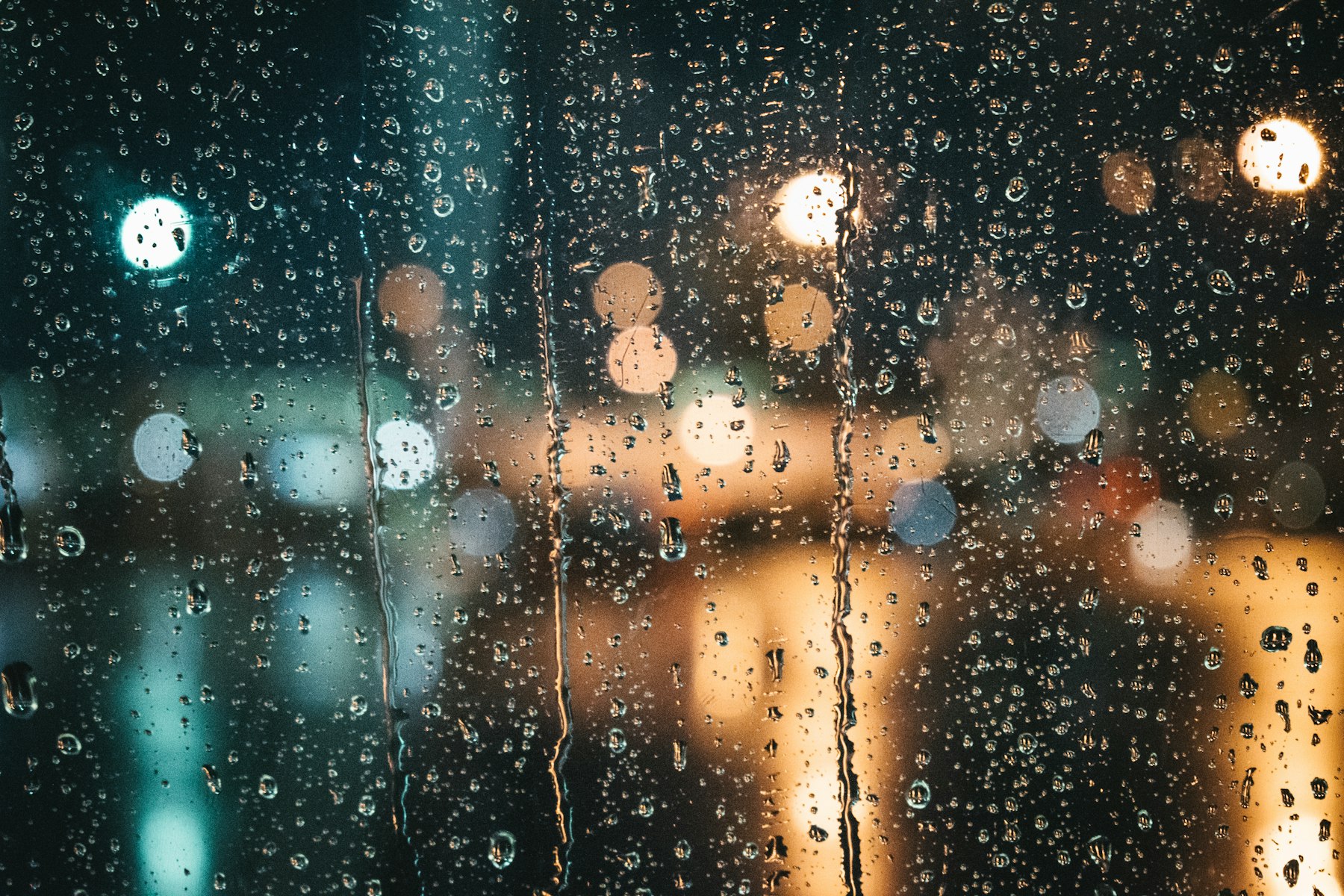 Regen auf einem Fenster, Stadtlichter dahinter